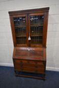 AN EARLY 20TH CENTURY OAK BUREAU BOOKCASE, with double lead glazed doors, atop a base with a fall