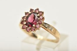A 9CT GOLD GEM SET CLUSTER RING, of an oval form, set with a central ovel cut garnet, in a