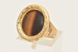 A YELLOW METAL TIGERS EYE RING, textured surround and band, rubbed unclear hallmark possibly 18ct,