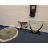 A GLASS SIDE TABLE, raised on metal legs, a circular glass top table, a console table, a wall clock,