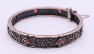 A silver and garnet bangle. 5.5 cm inner diameter.