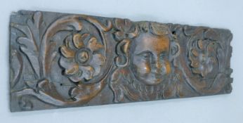 An 18th century carved oak panel centred with a cherub. 39.5 x 11.5 cm.