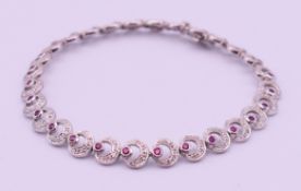 An 18 ct white gold and ruby bracelet. 18 cm long. 13.9 grammes total weight.