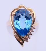 A 14 K gold ring with a pear shaped cut blue topaz and five small cut diamonds. Ring size M.