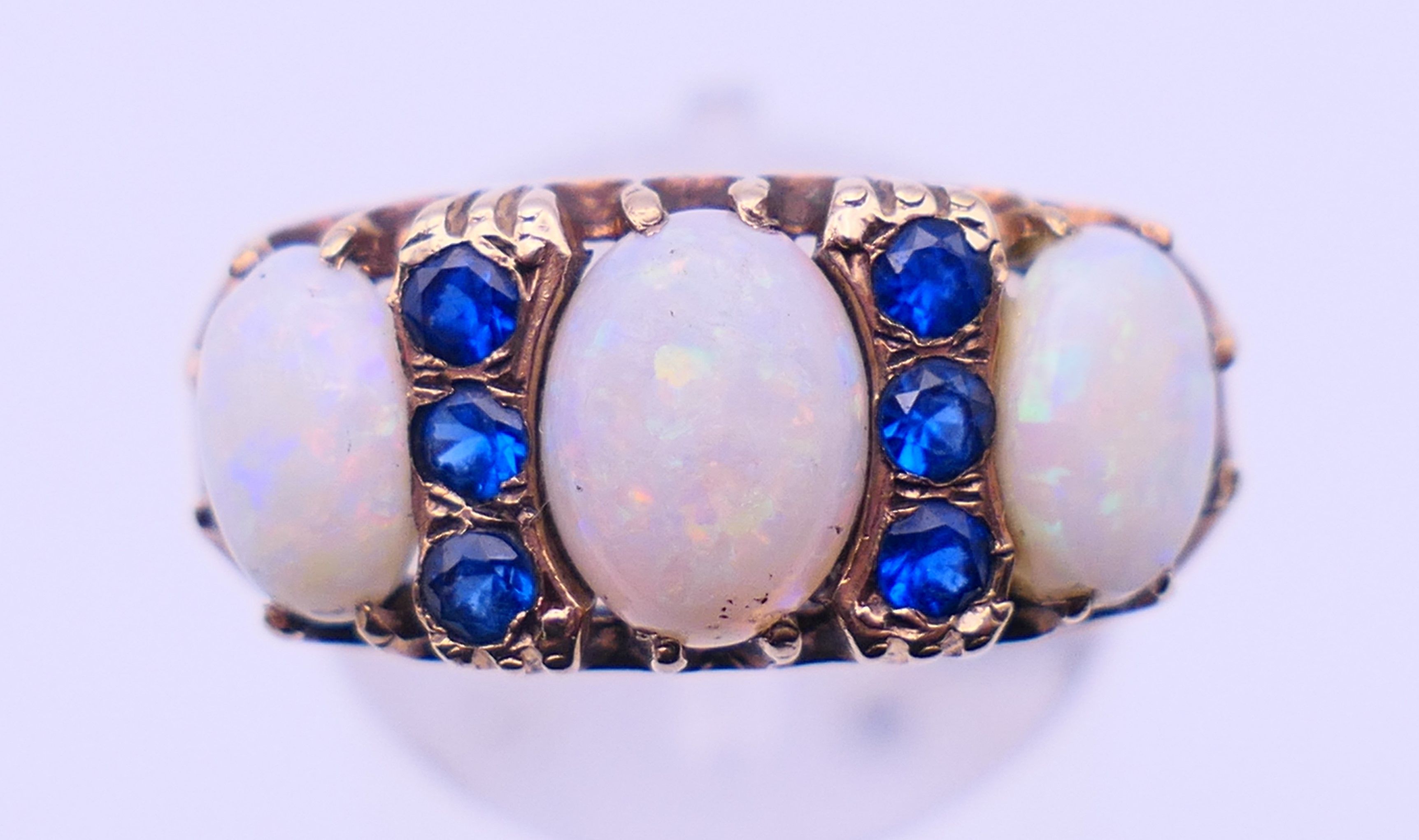 A 9 ct gold, opal and sapphire ring. Ring size Q. 4.8 grammes total weight.