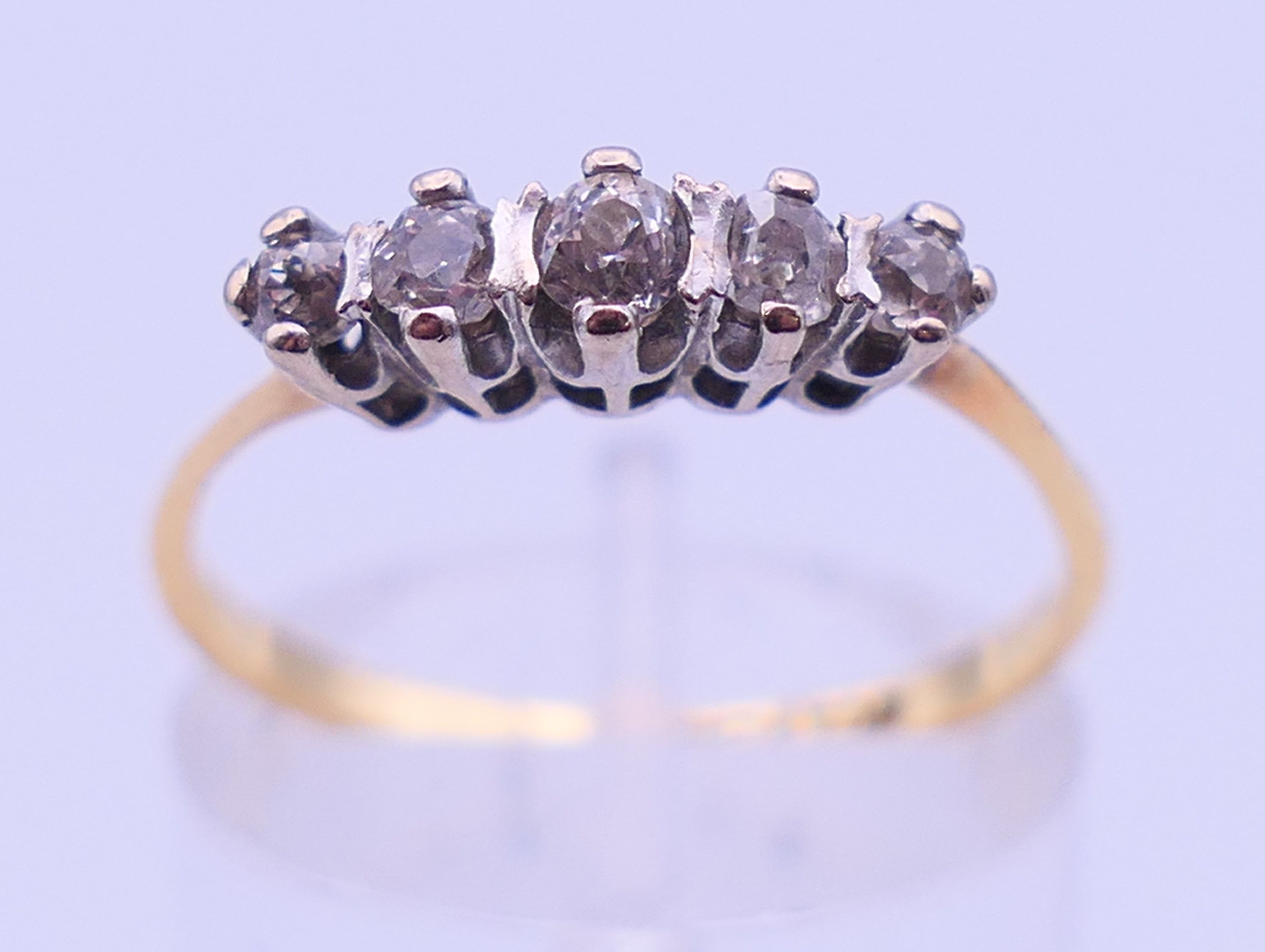 An 18 ct gold and platinum five-stone diamond ring. Ring size N/O. 2.1 grammes total weight.