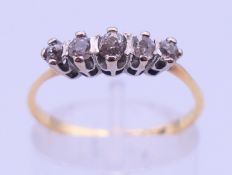 An 18 ct gold and platinum five-stone diamond ring. Ring size N/O. 2.1 grammes total weight.