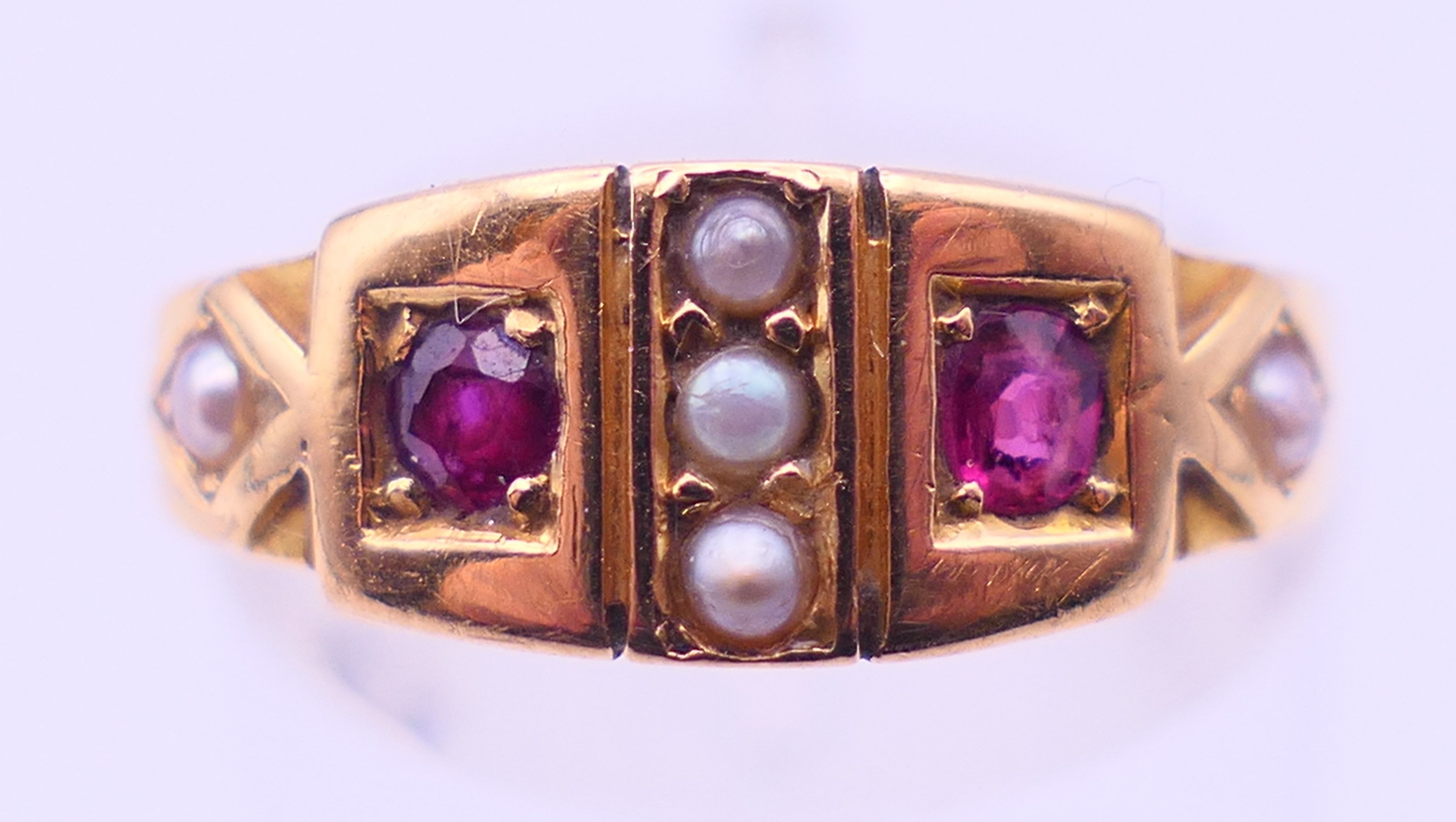An 18 ct gold, ruby and seed pearl ring. Ring size M. 3.2 grammes total weight.