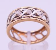 A 9 ct gold three-stone diamond pierced band-form ring. Ring size M/N. 3.1 grammes total weight.