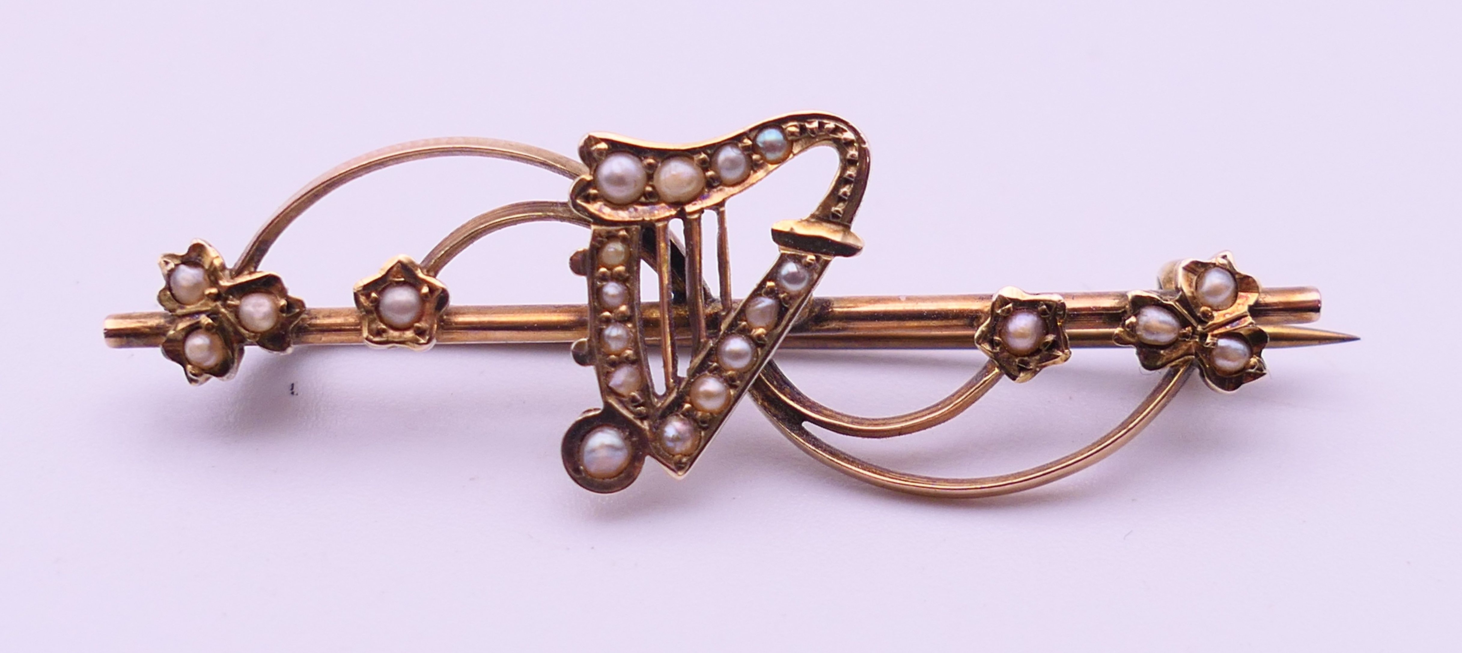 An Edwardian 9 ct gold and seed pearl harp bar brooch. 5 cm long. 2.9 grammes total weight.