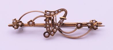 An Edwardian 9 ct gold and seed pearl harp bar brooch. 5 cm long. 2.9 grammes total weight.