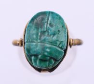 An Egyptian Revival gilt metal ring set with a pottery scarab beetle.