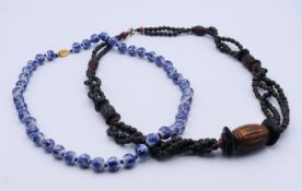 Two Chinese necklaces. The porcelain example 58 cm long.