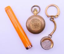 A brass sovereign holder, another coin holder and a cased amber cheroot holder.
