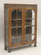 An early 20th century glazed carved oak bookcase. 89.5 x 120.5 cm.