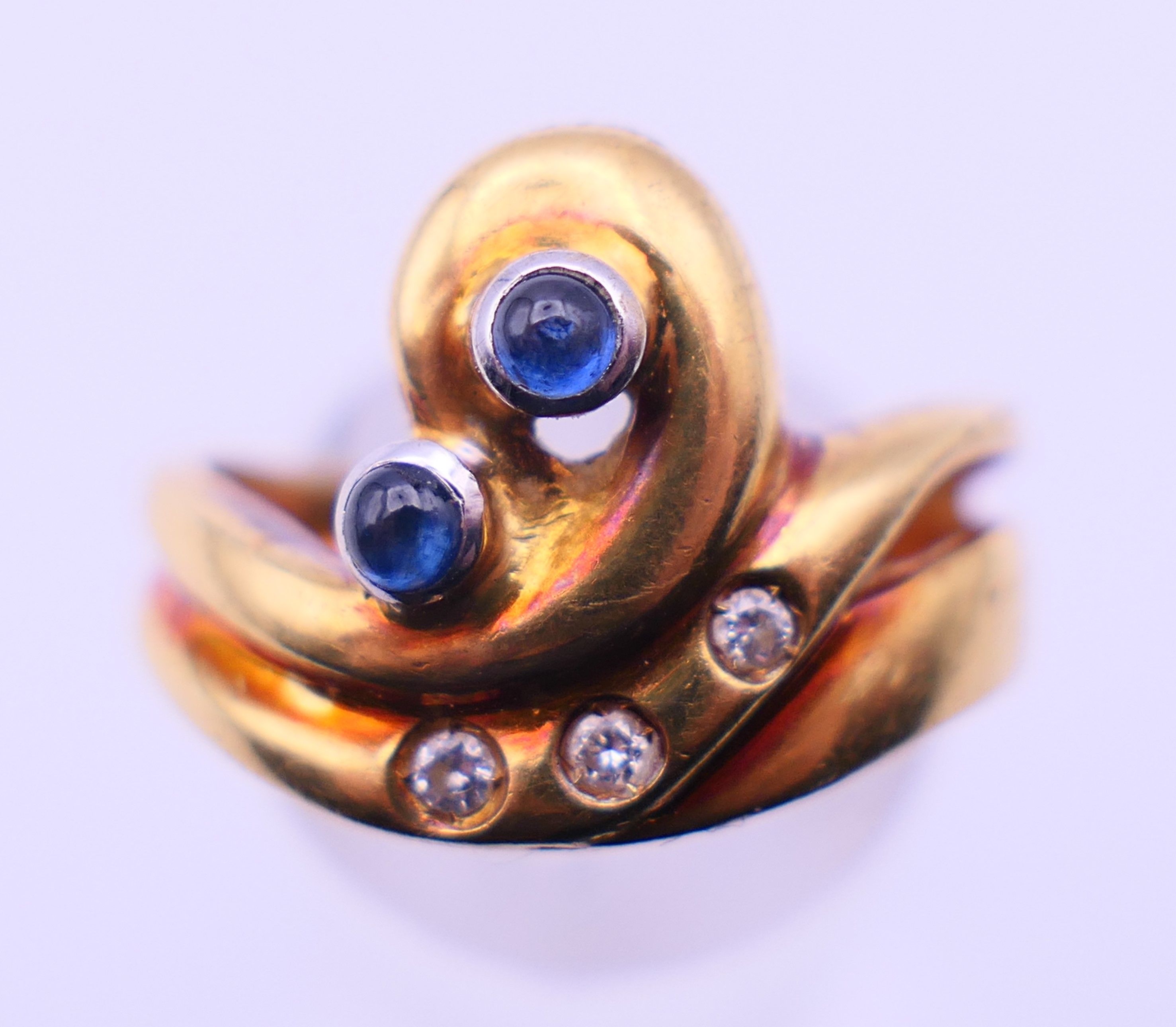 A contemporary 18 ct gold, diamond and sapphire ring. Ring size P/Q. 7.6 grammes total weight.