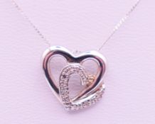A 9 ct white gold and diamond double heat pendant on a 9 ct white gold chain. Pendant 1.