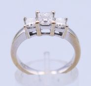 An 18 K white gold three-stone diamond ring. Ring size N.