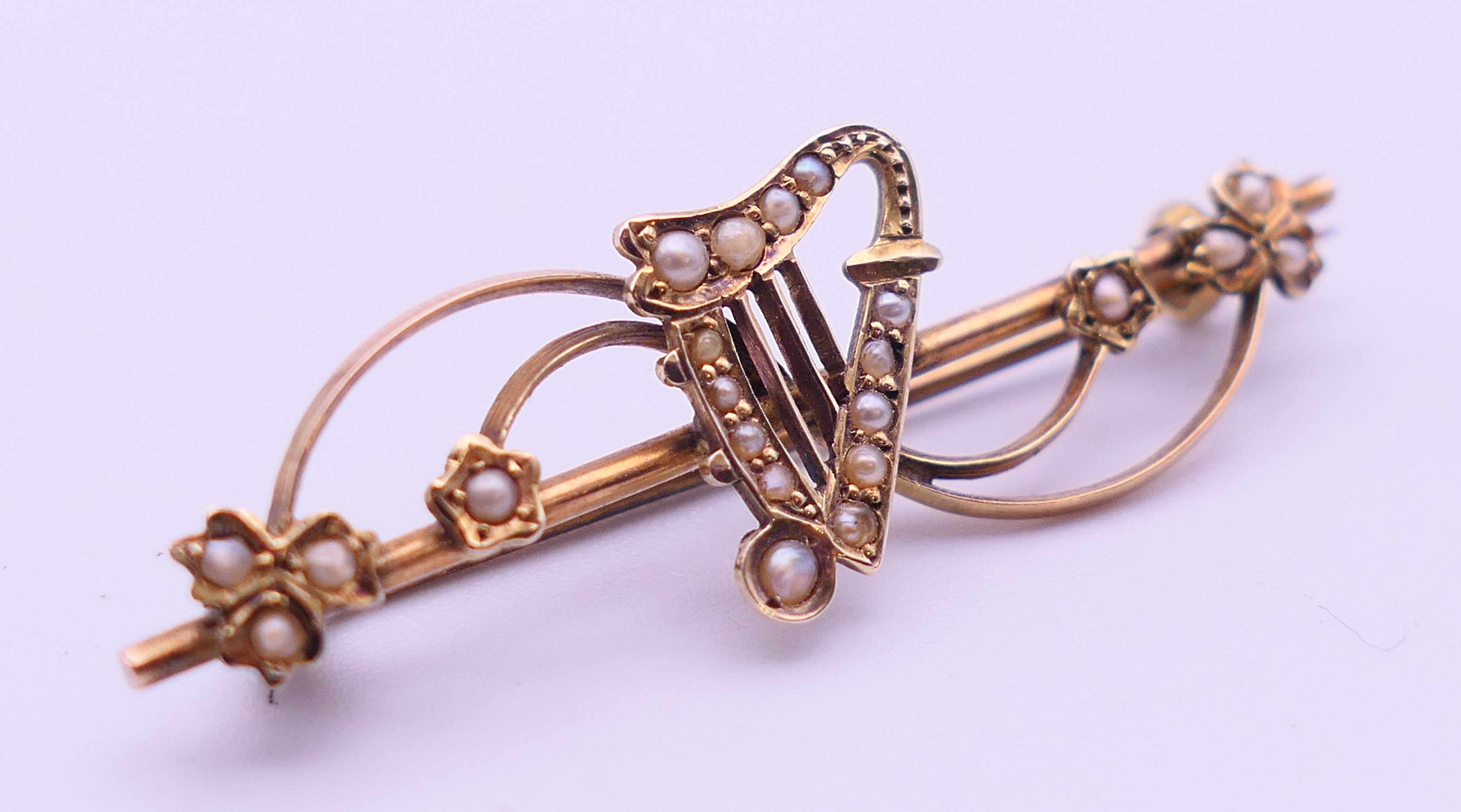 An Edwardian 9 ct gold and seed pearl harp bar brooch. 5 cm long. 2.9 grammes total weight. - Image 2 of 4