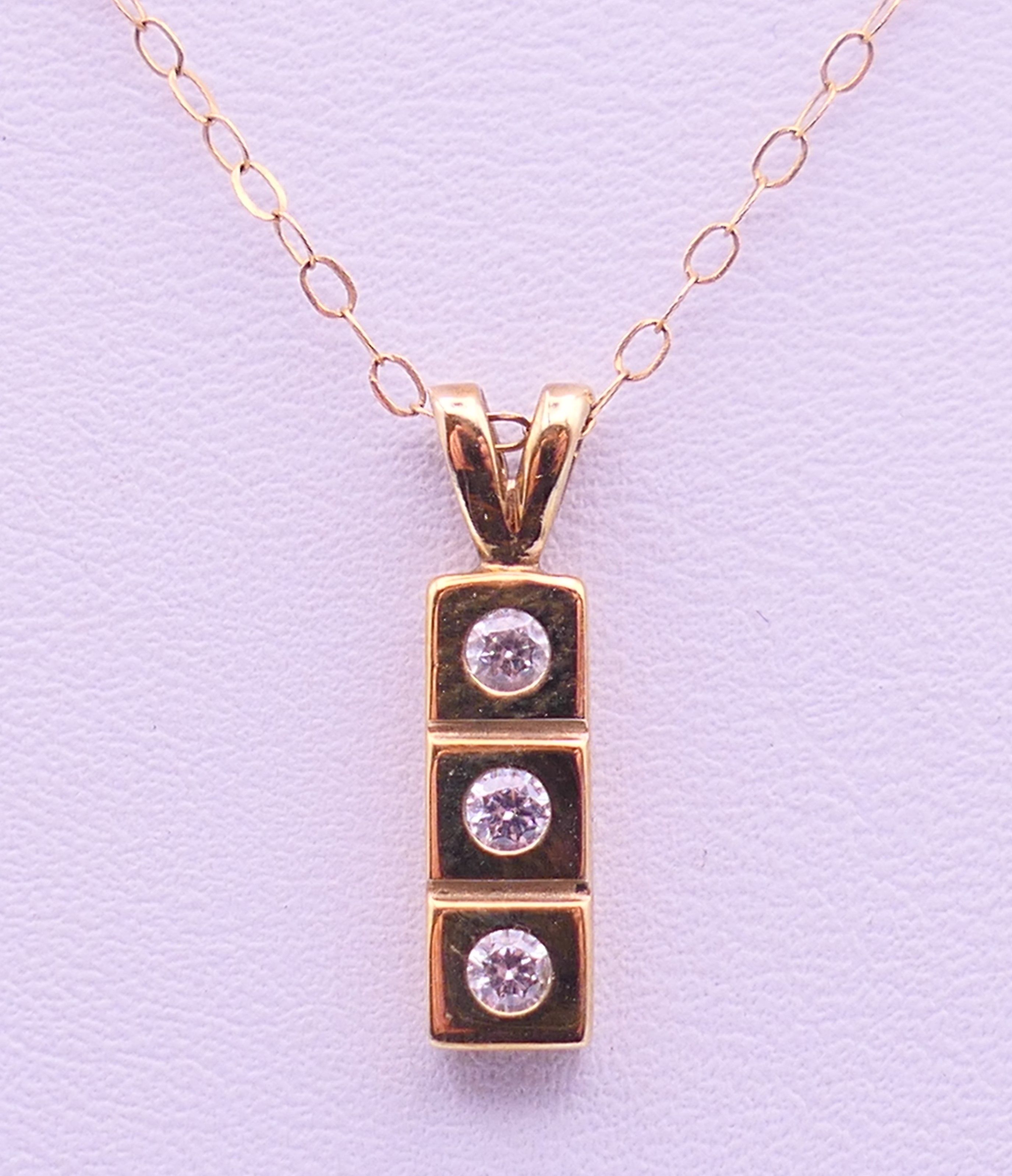 A 9 ct gold three-stone pendant on a 9 K gold chain. Pendant 1.