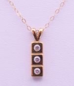 A 9 ct gold three-stone pendant on a 9 K gold chain. Pendant 1.