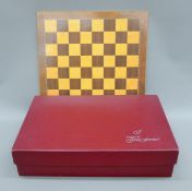 A boxed Gino Ferrari chess set and a chessboard. The latter 39.5 cm square.