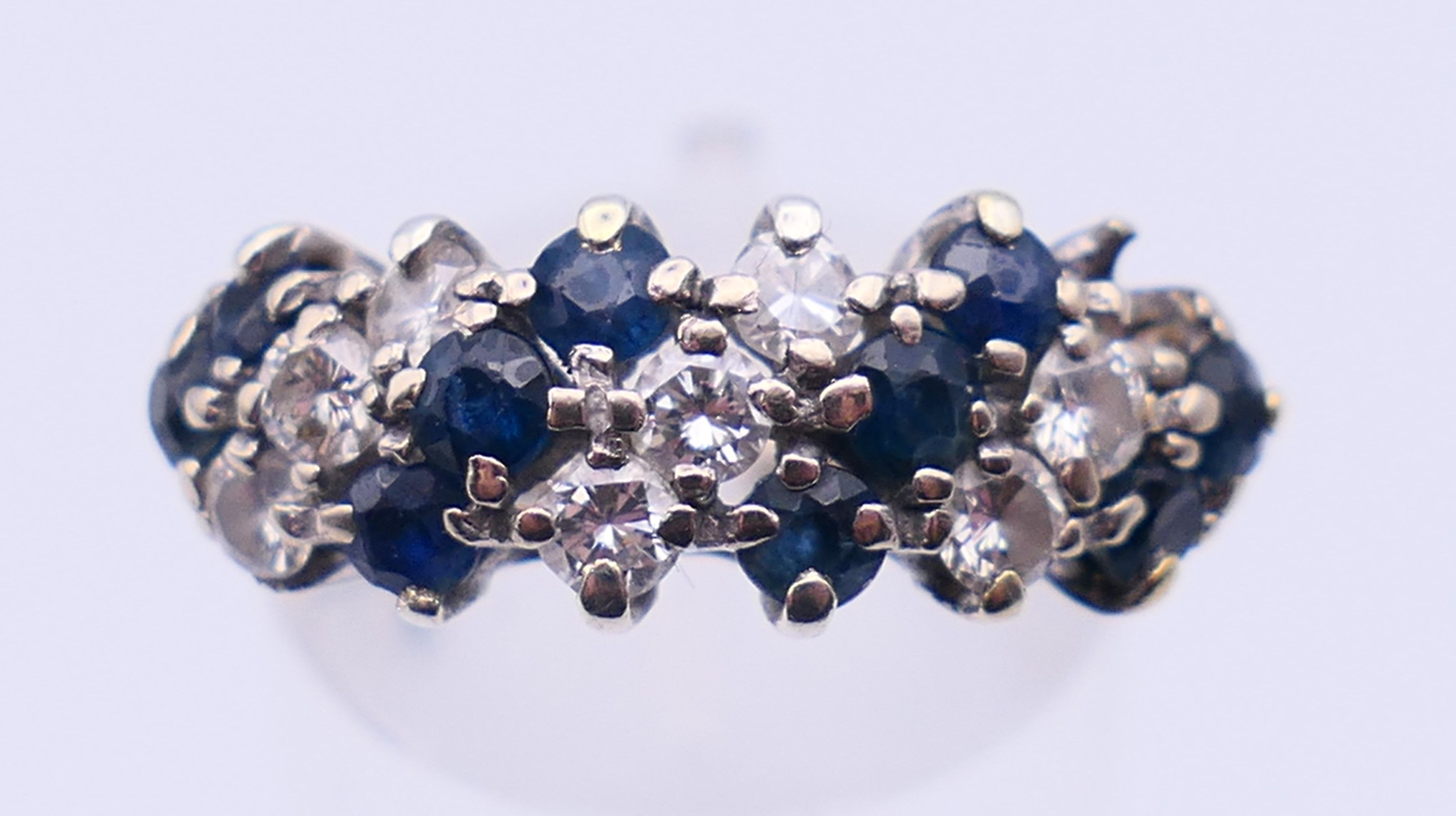 An unmarked white gold or platinum, diamond and sapphire ring. Ring size N. 4 grammes total weight.