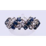 An unmarked white gold or platinum, diamond and sapphire ring. Ring size N. 4 grammes total weight.