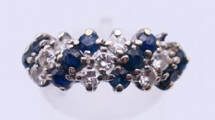 An unmarked white gold or platinum, diamond and sapphire ring. Ring size N. 4 grammes total weight.