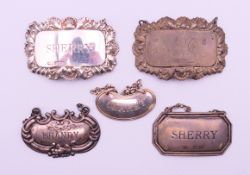 Five silver wine bottle labels. The largest 6 cm wide.