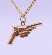 A 9 ct gold pistol gun-form pendant on a 9 ct gold chain. Pistol 3 cm long, chain 44 cm long. 4.