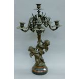 A bronze candelabra decorated with cherubs. 69 cm high.