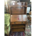 An oak Arts and Crafts bureau with a raised back f