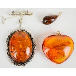 A large pressed amber heart shaped pendant with 14k gold pendant loop, large silver brooch set