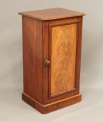 A mid-19th century mahogany bedside cabinet - with a well-figured panelled door, the interior with a