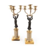 A Pair of Patinated and Parcel Gilt Metal Three-Light Candelabra, early 20th century, of figural
