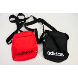 Two Adidas small item shoulder bags, one red and one black, bags appear in unused condition.