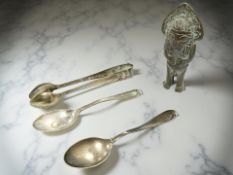 A pair of silver tongs, two teaspoons, and an eastern brass erotic statue,