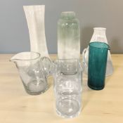 A group of large glass objects including tall vases, coloured glass water jug,