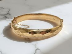 A 9ct yellow gold bangle with chevron decoration, 60 mm x 55 mm.