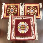 Three Chinese woolen rugs on red ground, the largest 75 cm x 65 cm.