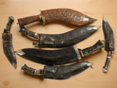 Five various kukri knives in sheathes, and a similar carved wooden example.