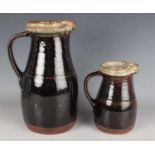 A graduated pair of Richard Batterham studio pottery stoneware jugs, the ash glazed rims and