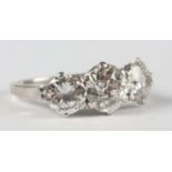 A platinum and diamond three stone ring, claw set with a row of circular old cut diamonds,