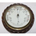 An aneroid barometer with ceramic circular dial in oak rope-twist and brass mounted circular case,