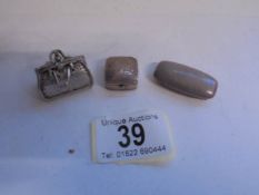 Three white metal pill boxes including one in the shape of a handbag.