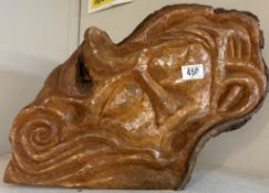 A carved wooden face sculpture with flowing lines & abstract shapes