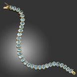 AN AQUAMARINE BRACELET, composed of a line of oval-shaped aquamarines in claw settings, mounted in