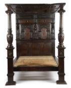 AN OAK TESTER BED C.1600 AND LATER the headboard with a pair of arched foliate carved panels
