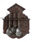 A TREEN OAK SPOON RACK 19TH CENTURY with chipped carved whorl and lunette decoration, with six